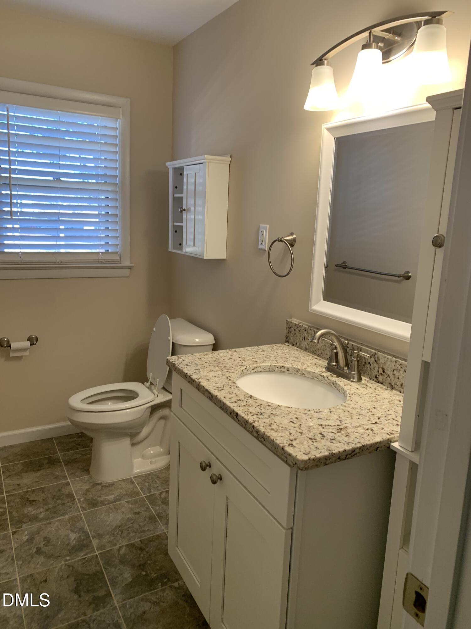 41 Tant Road Zebulon, NC 27597 - Photo 8 of 8 a bathroom with a granite countertop sink a toilet and a mirror