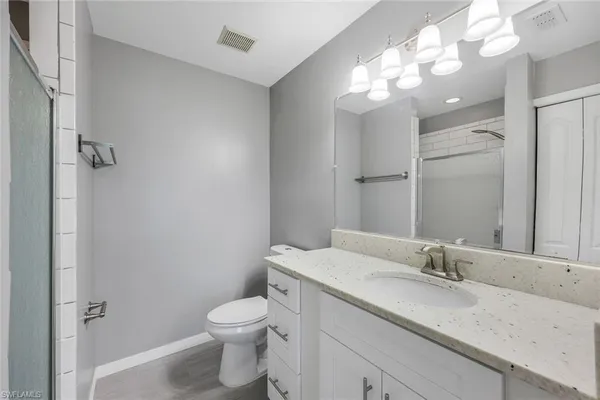 a bathroom with a granite countertop sink a toilet and a mirror