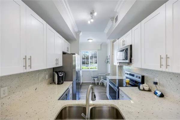 a kitchen with stainless steel appliances a sink a stove a microwave a sink a refrigerator and cabinets