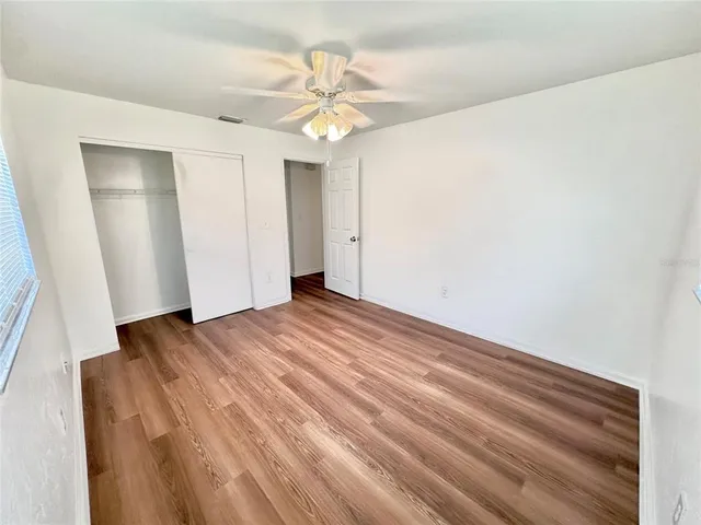 a view of a room with wooden floor and ceiling fan