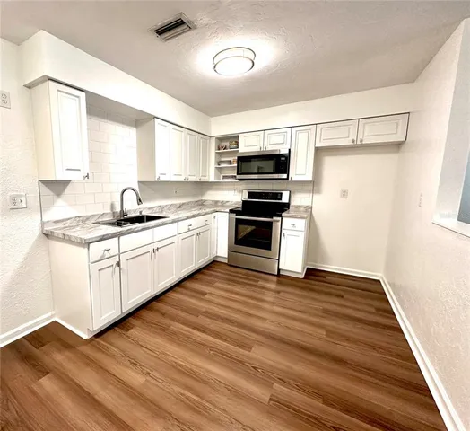 a kitchen with stainless steel appliances a sink dishwasher a refrigerator and cabinets with wooden floor