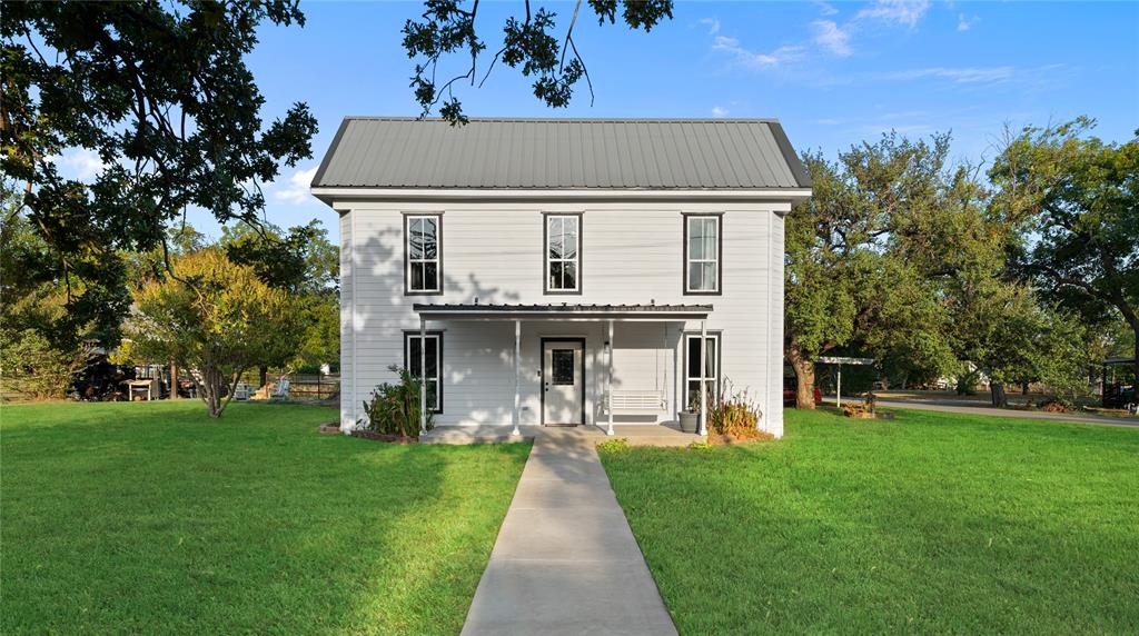 202 North Kickapoo Street Lipan, TX 76462 - Photo 2 of 38 Two-story residence featuring white siding, a metal roof, and a covered front porch with columns