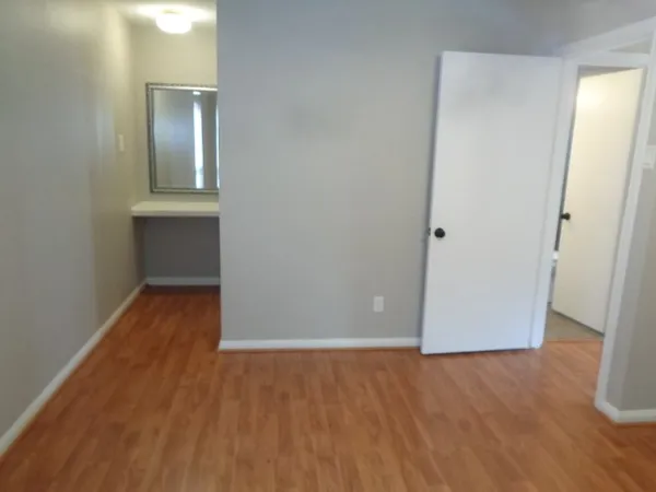 an empty room with wooden floor and mirror