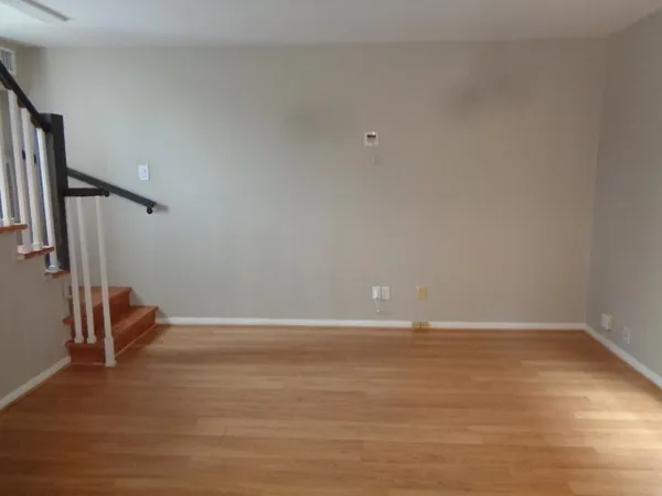a view of an empty room with wooden floor and chair