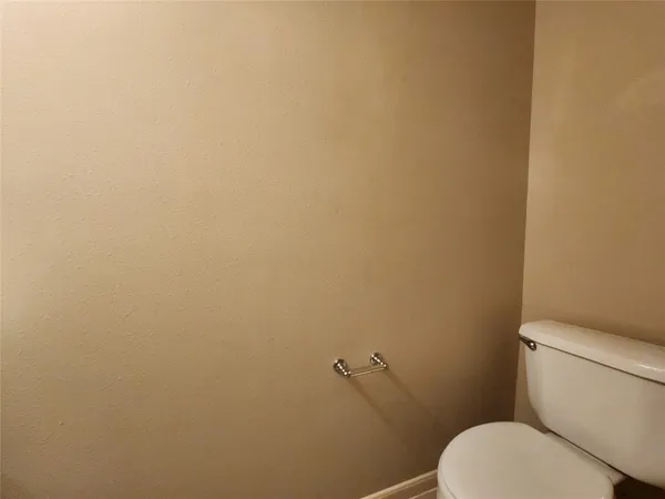 a white toilet sitting next to a white wall