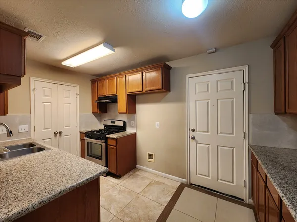 a kitchen with granite countertop a sink stove and refrigerator