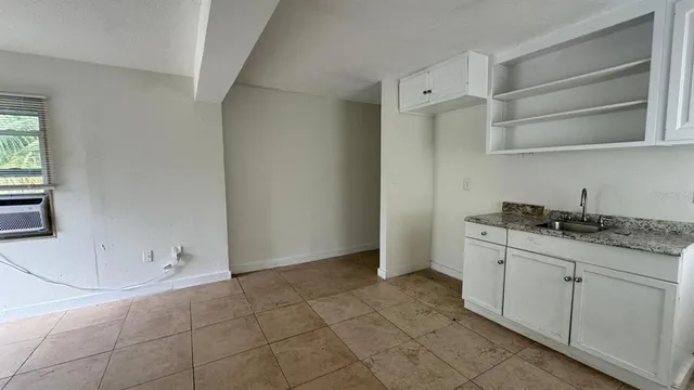 a room with granite countertop white cabinets and window