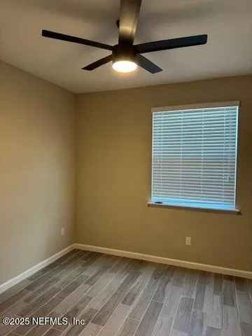 an empty room with a ceiling fan and window