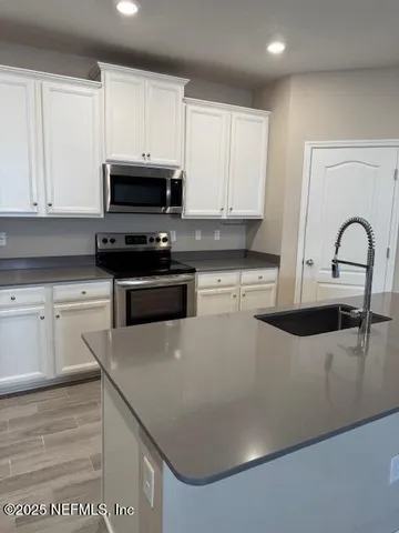 a kitchen with granite countertop white cabinets and stainless steel appliances