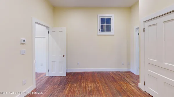a view of an empty room with wooden floor and closet