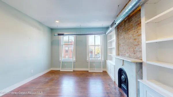 a view of empty room with fireplace and wooden floor