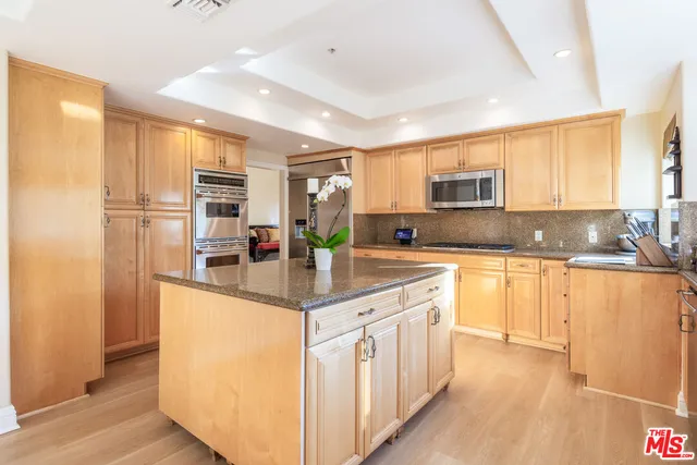 a kitchen with kitchen island granite countertop a sink counter top space appliances and cabinets