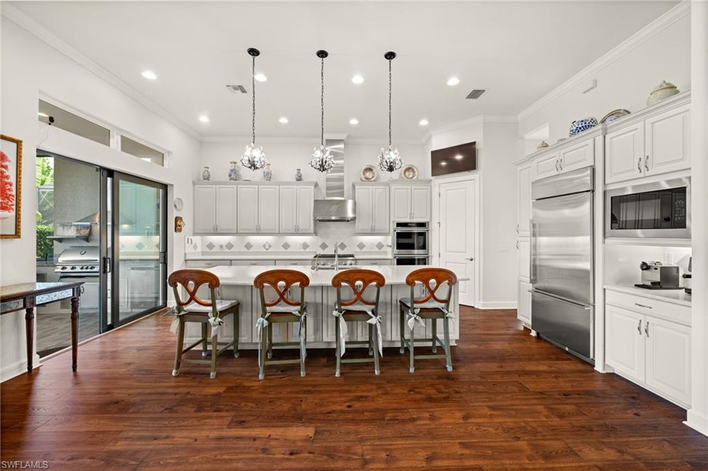 9509 Montelanico Loop Naples, FL 34119 - Photo 16 of 50 a kitchen with stainless steel appliances granite countertop a dining table chairs refrigerator and microwave