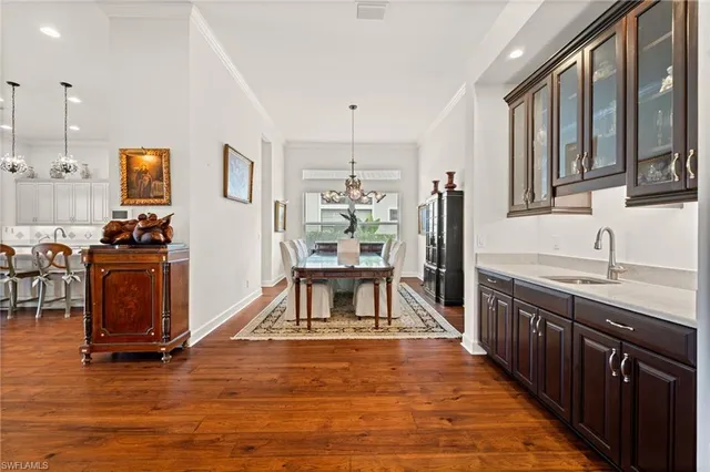 a kitchen with stainless steel appliances granite countertop a stove top oven a sink dishwasher a dining table and chairs with wooden floor