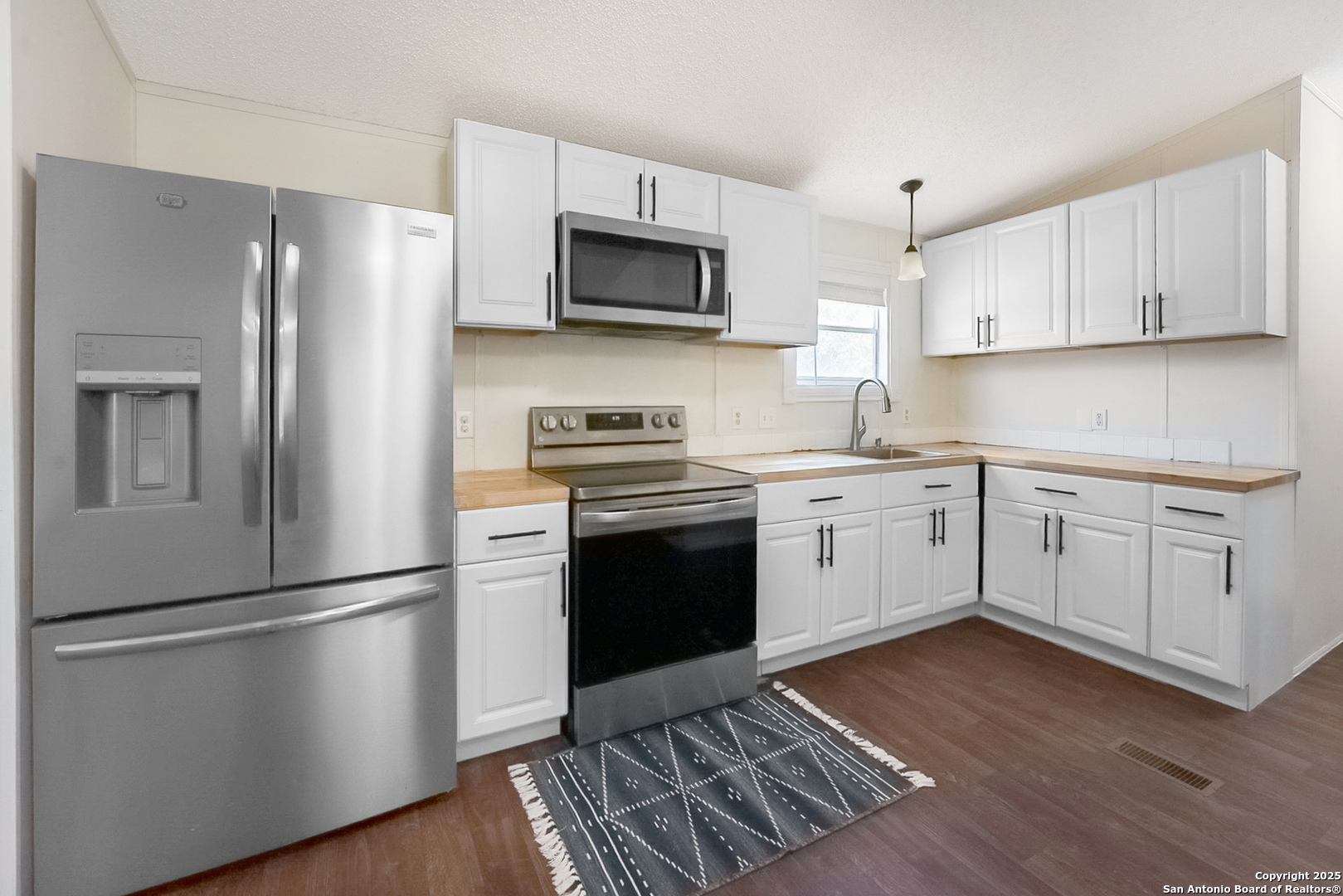 25335 Pleasanton Road San Antonio, TX 78264 - Photo 16 of 26 a kitchen with a refrigerator stove and white cabinets