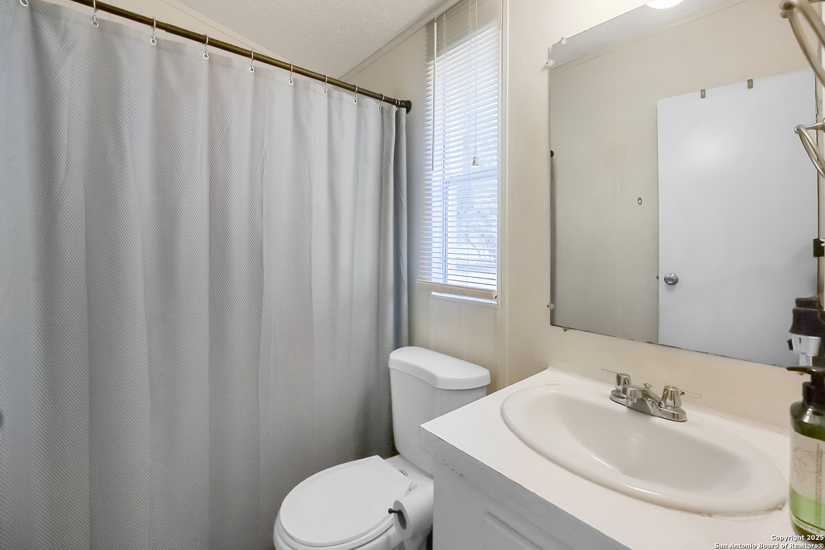 25335 Pleasanton Road San Antonio, TX 78264 - Photo 24 of 26 a bathroom with a sink a toilet and shower curtain