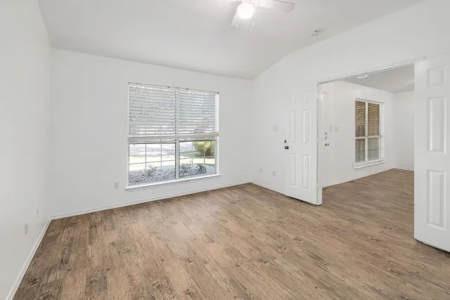 an empty room with wooden floor and windows
