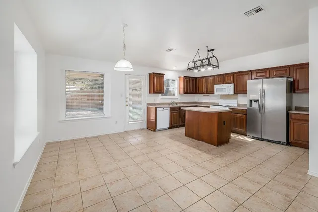 a kitchen with stainless steel appliances granite countertop a stove a sink dishwasher and a refrigerator