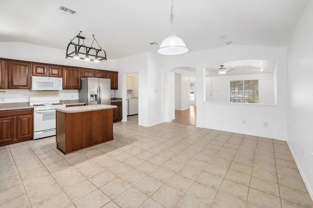 a kitchen with stainless steel appliances a sink a stove a refrigerator cabinets and a window