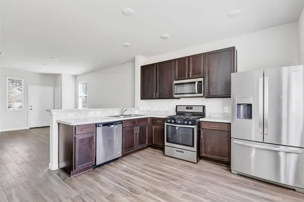a kitchen with stainless steel appliances granite countertop a stove a refrigerator and a microwave oven with wooden floor