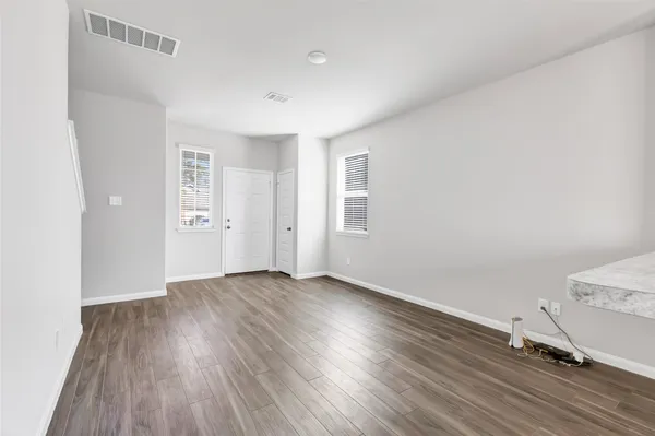 an empty room with wooden floor and windows