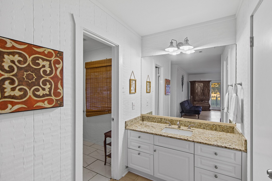 411 Whitetail Ridge Dripping Springs, TX 78620 - Photo 14 of 40 a bathroom with a granite countertop sink and a mirror