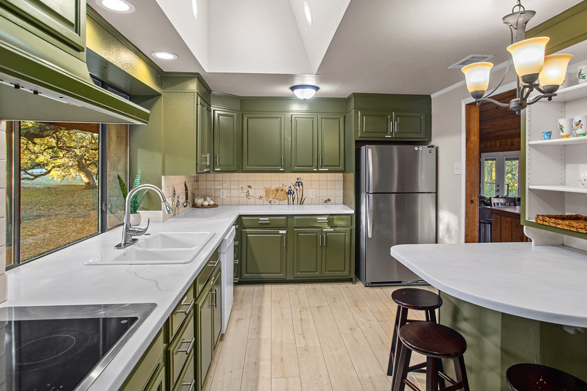 411 Whitetail Ridge Dripping Springs, TX 78620 - Photo 8 of 40 a kitchen with a table chairs refrigerator and cabinets