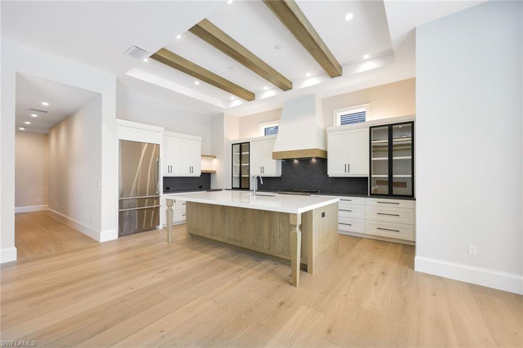 16728 Enclave Circle Naples, FL 34110 - Photo 14 of 50 a large white kitchen with stainless steel appliances kitchen island granite countertop a stove and a refrigerator