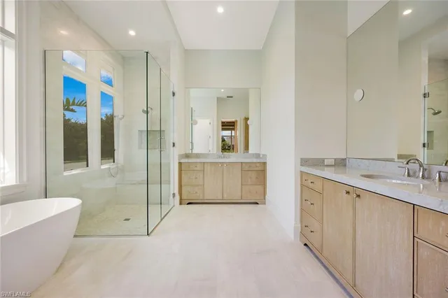 a bathroom with a double vanity sink mirror and a bathtub