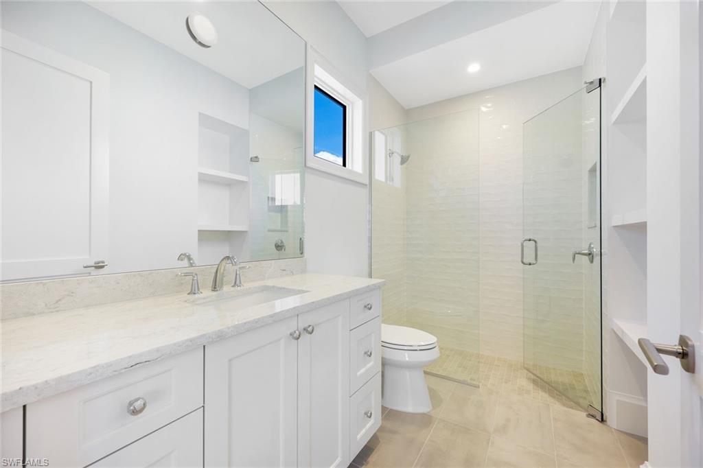16728 Enclave Circle Naples, FL 34110 - Photo 28 of 50 a bathroom with a granite countertop sink a toilet and a mirror