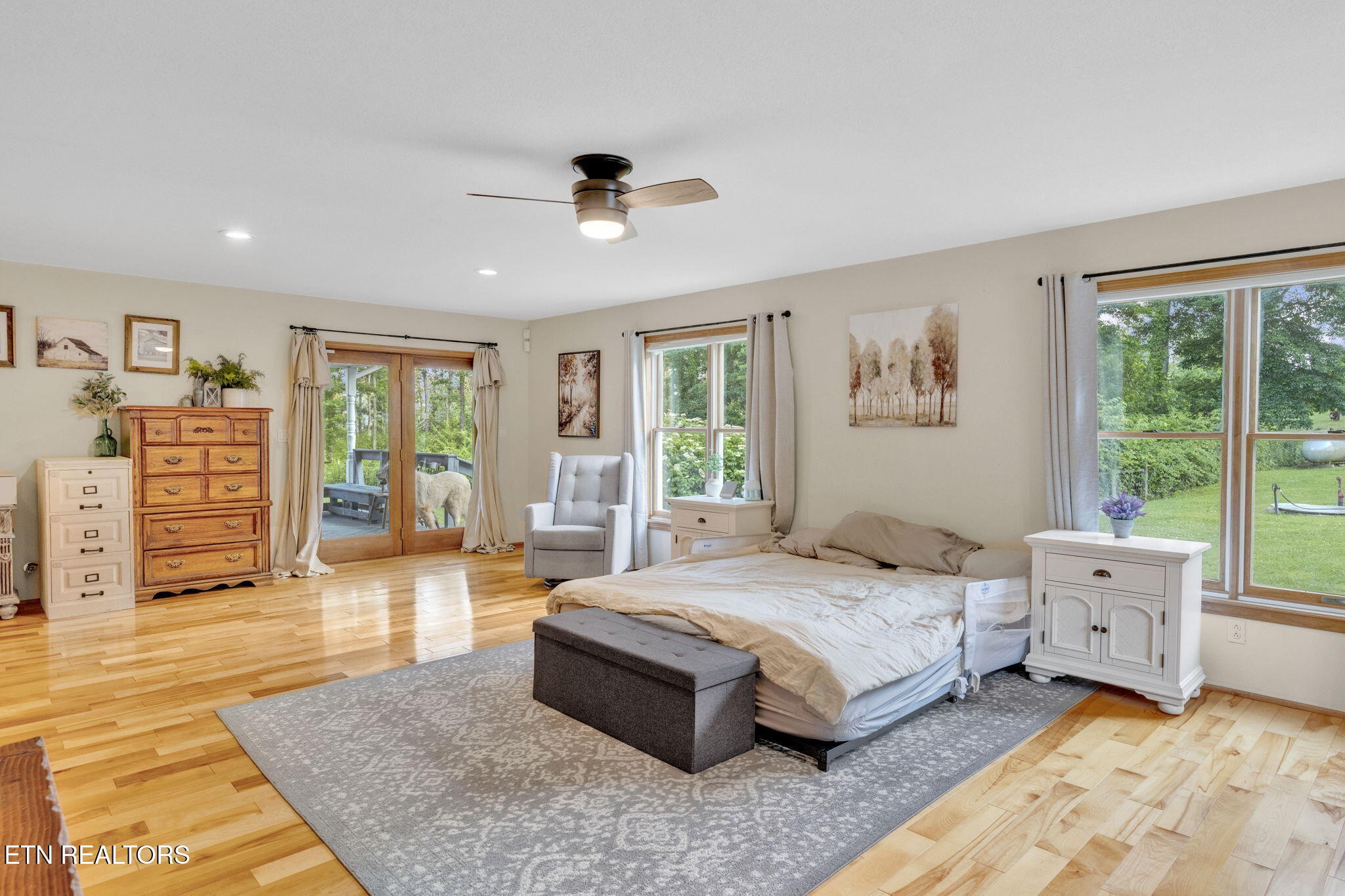 596 Clifty Creek Road Oakdale, TN 37829 - Photo 18 of 60 a spacious bedroom with a large bed a chandelier and windows