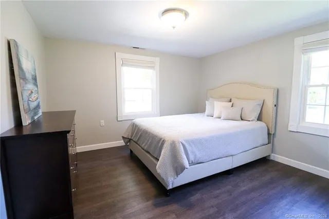 a bedroom with a bed table chair and a window