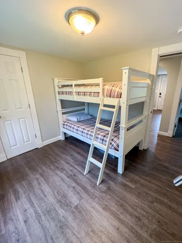 a view of a room with wooden floor white walls and windows