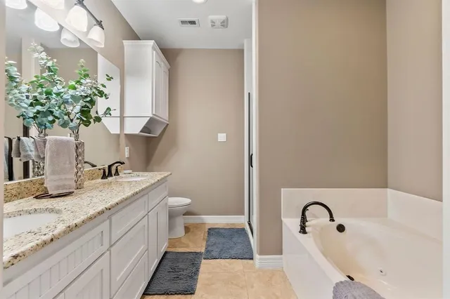 a bathroom with a granite countertop tub sink and mirror