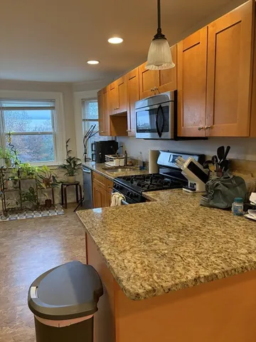 a kitchen with stainless steel appliances granite countertop a sink a stove and a wooden cabinets