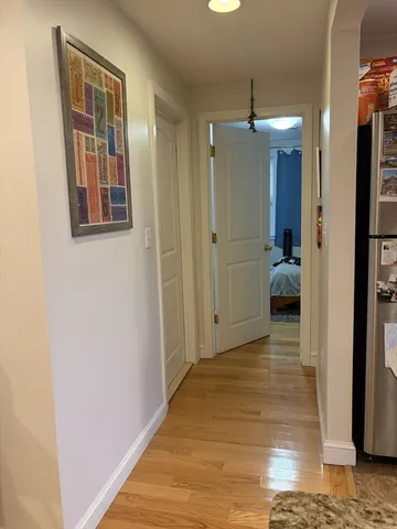 a view of a hallway with wooden floor and a bathroom
