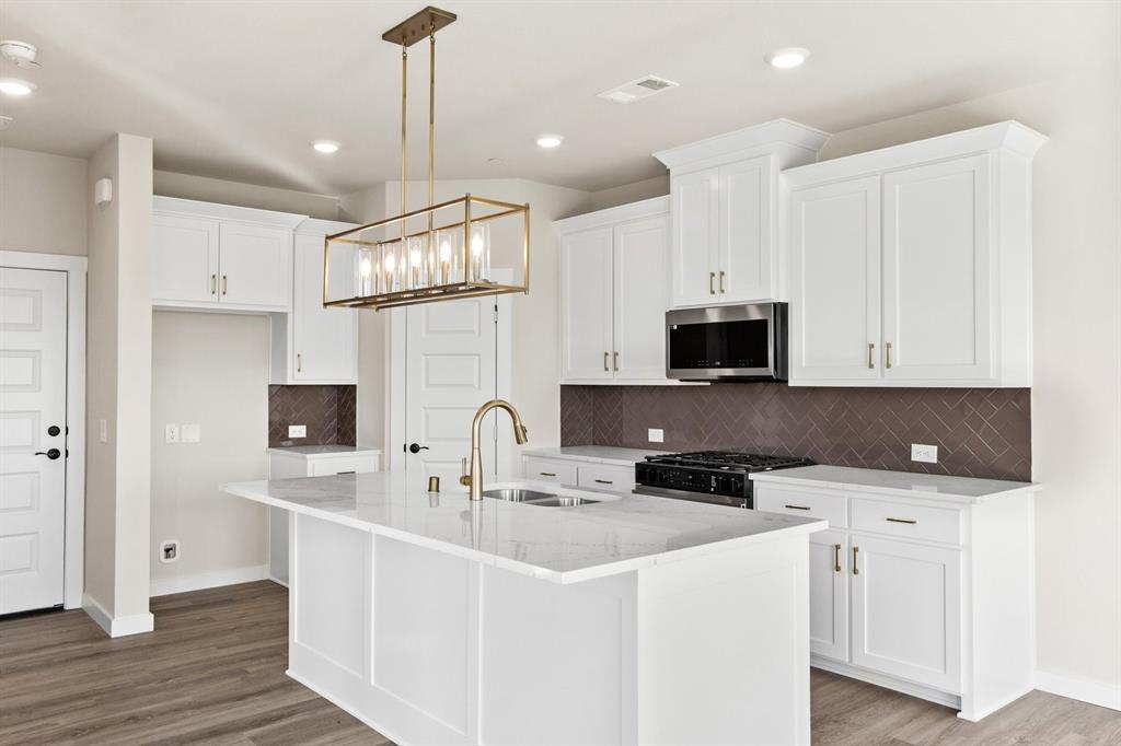 2028 Aldrich Road Celina, TX 75009 - Photo 14 of 40 a kitchen with stainless steel appliances a sink a stove a microwave a center island and cabinets