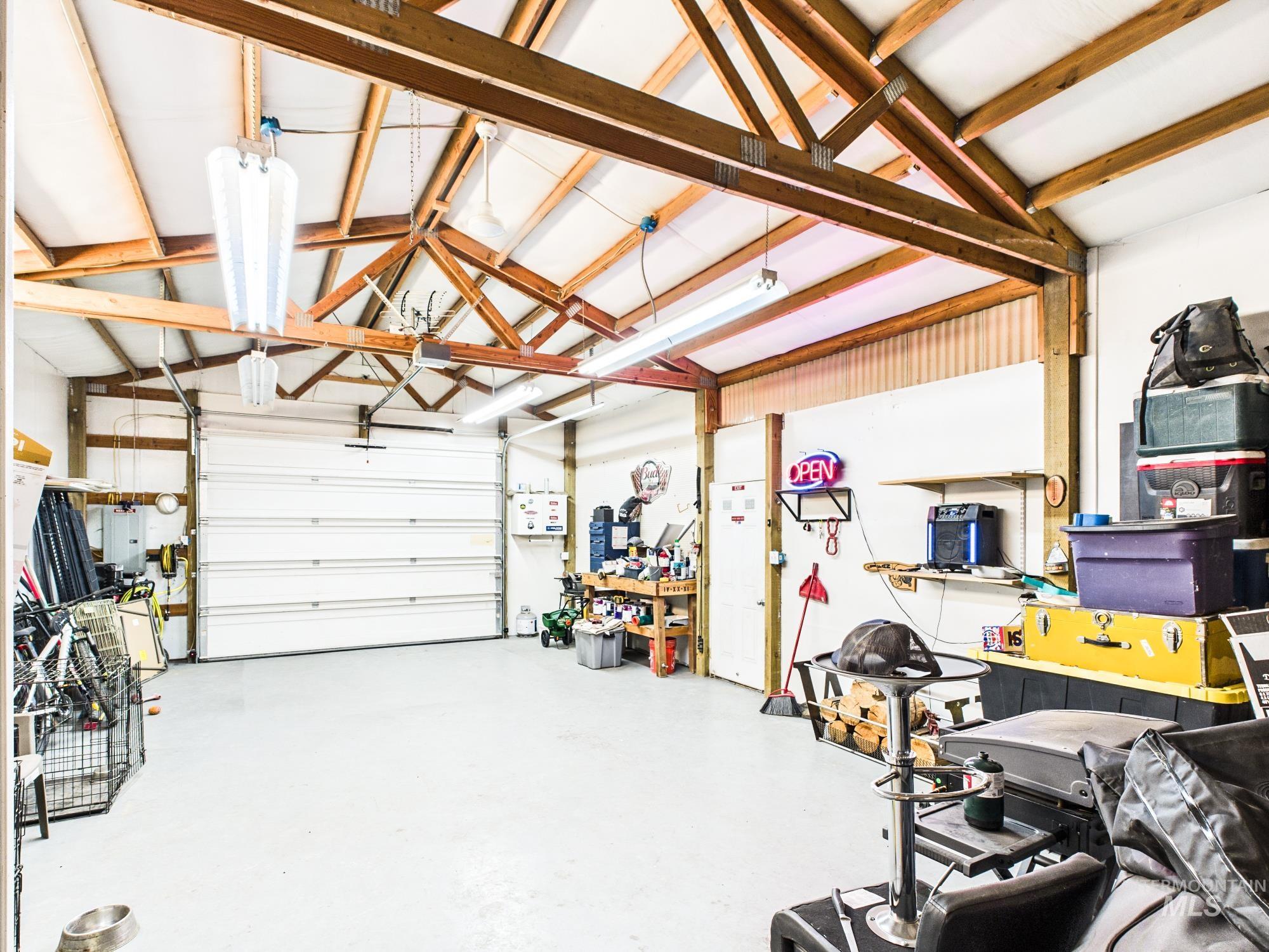 3422 6th Street Lewiston, ID 83501 - Photo 37 of 43 Spacious garage featuring exposed wood beam ceiling, multiple fluorescent light fixtures, two large roll-up garage doors, and a concrete floor