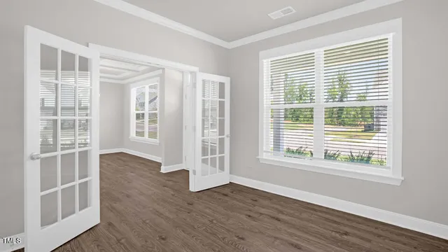 a view of an empty room with wooden floor and windows