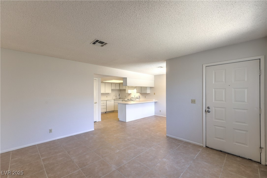 5829 Smoke Ranch Road, Unit C Las Vegas, NV 89108 - Photo 12 of 25 Unfurnished living room featuring a textured ceili