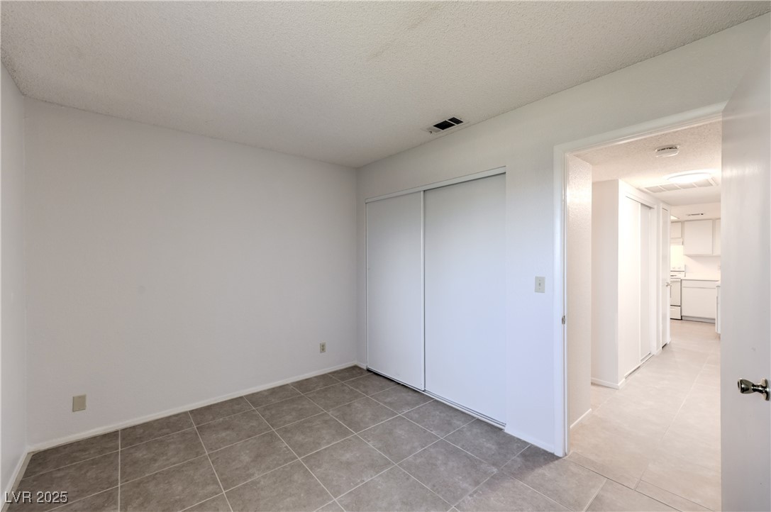 5829 Smoke Ranch Road, Unit C Las Vegas, NV 89108 - Photo 18 of 25 Unfurnished bedroom featuring a closet, light tile