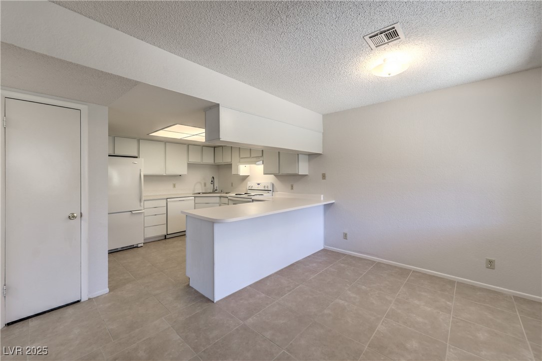 5829 Smoke Ranch Road, Unit C Las Vegas, NV 89108 - Photo 4 of 25 Kitchen with a peninsula, white appliances, light