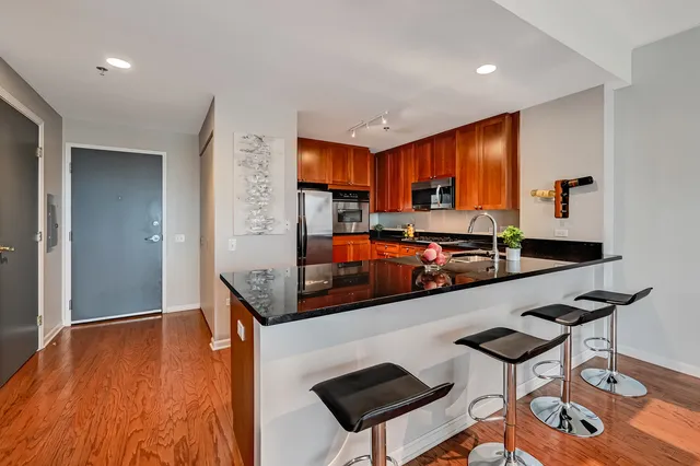 a room with stainless steel appliances kitchen island granite countertop a refrigerator and a stove top oven