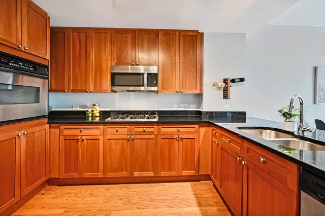 a kitchen with stainless steel appliances granite countertop wooden cabinets a stove top oven with a sink and dishwasher