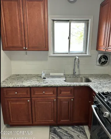 a kitchen with granite countertop a sink a stove and cabinets