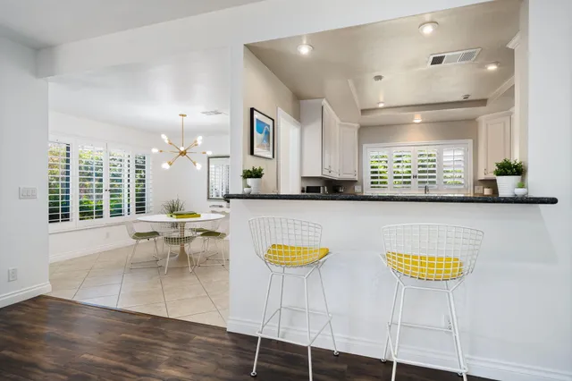 a kitchen with granite countertop white cabinets appliances and a window