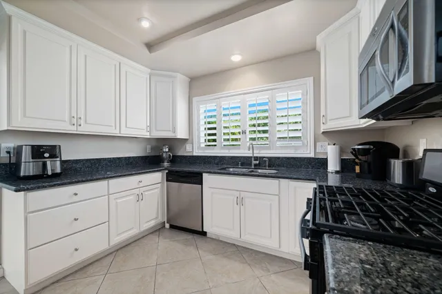 a kitchen with granite countertop white cabinets and a sink