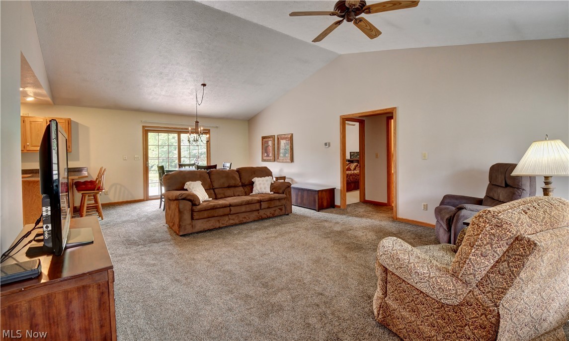 3318 Simpson Road Southeast Dennison, OH 44621 - Photo 7 of 31 Living room with lofted ceiling, light carpet, ceiling fan with notable chandelier, and a textured ceiling