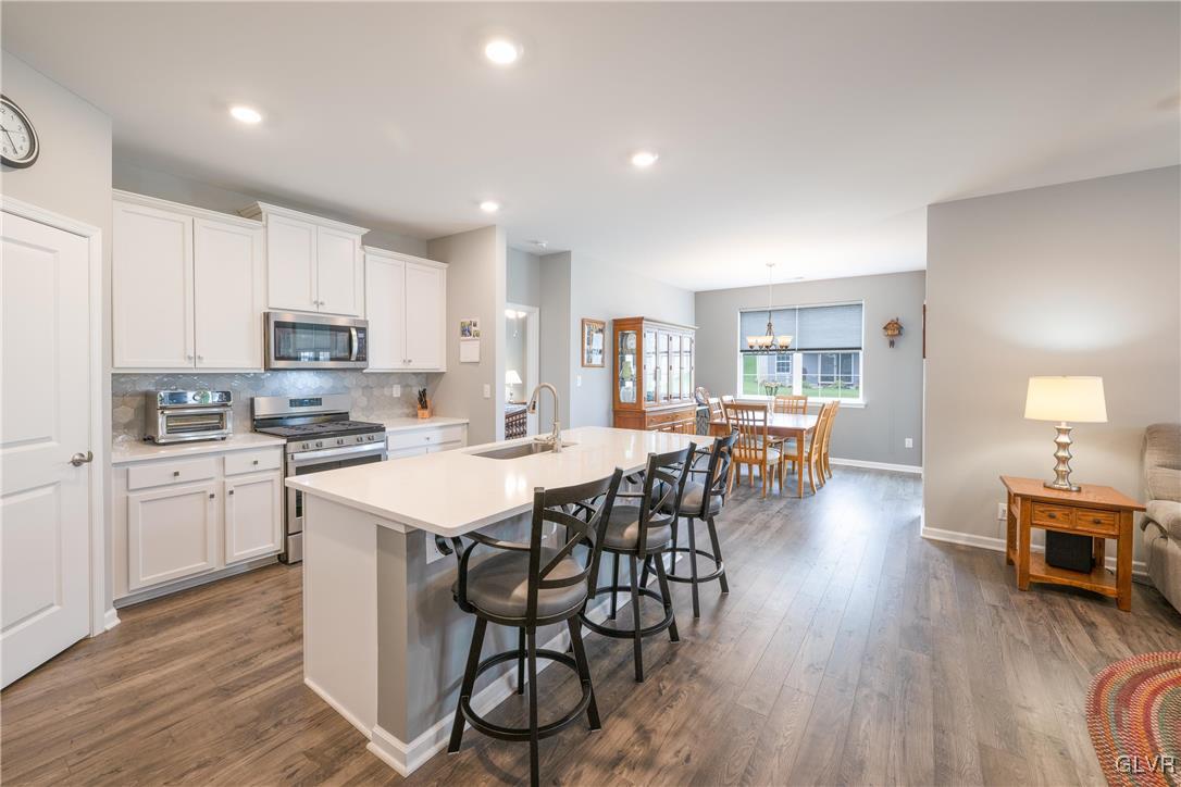 8078 Schaefer Crest Breinigsville, PA 18031 - Photo 11 of 35 a kitchen with stainless steel appliances granite countertop a stove a refrigerator a kitchen island with a dining table and chairs