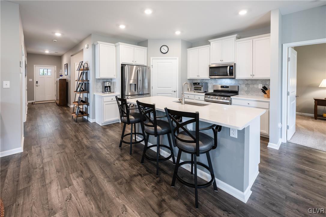8078 Schaefer Crest Breinigsville, PA 18031 - Photo 8 of 35 a kitchen with stainless steel appliances a microwave a stove a sink a refrigerator and white cabinets with wooden floor